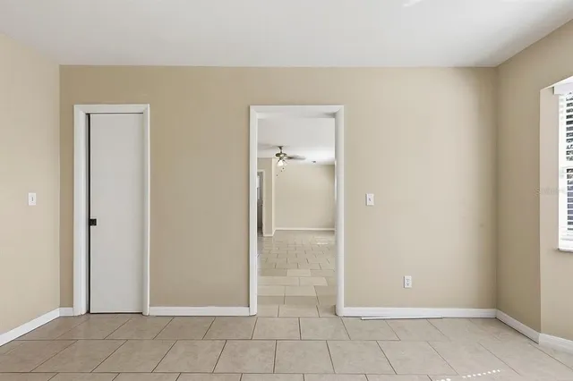 a view of an empty room and chandelier fan