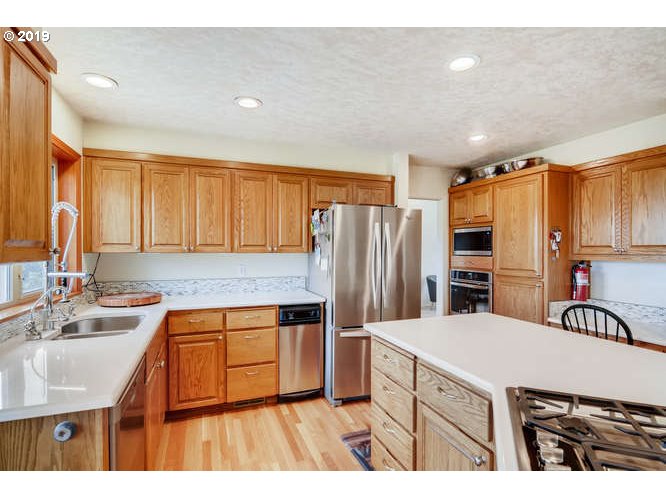 13848 Southwest Whitmore Road Hillsboro, OR 97123 - Photo 10 of 29 a kitchen with kitchen island a counter top space a sink a refrigerator and a cabinets