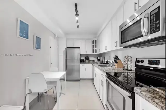 a kitchen with stainless steel appliances a stove a sink dishwasher a refrigerator white cabinets and wooden floor