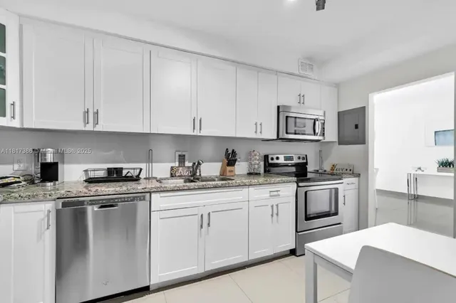 a kitchen with granite countertop white cabinets sink and stainless steel appliances