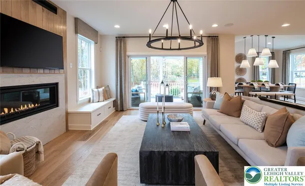 a living room with furniture kitchen view and a chandelier