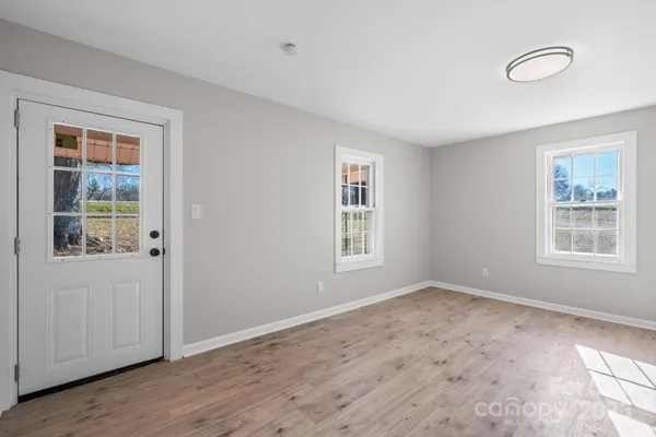 a view of an empty room with wooden floor and a window