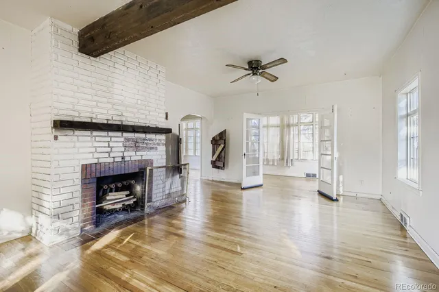 a view of an empty room with wooden floor fireplace and a window