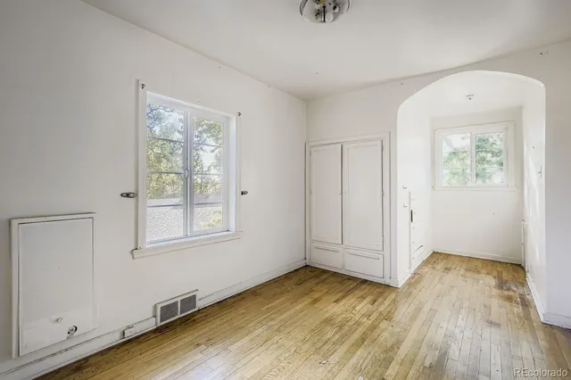 an empty room with wooden floor and windows