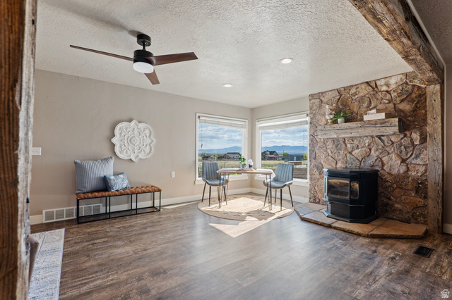 115 East 1600th Street North Santaquin, UT 84655 - Photo 6 of 52 Living area featuring wood-finish flooring, a stone accent wall with a built-in wood mantel, and large windows