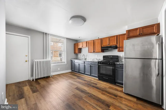 a kitchen with granite countertop stainless steel appliances a refrigerator cabinets and wooden floor
