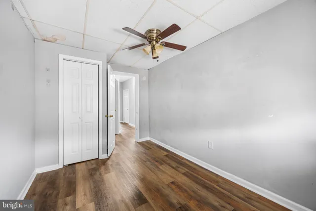 a view of a hallway with wooden floor and a ceiling fan