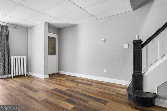 a view of an empty room with wooden floor and stairs