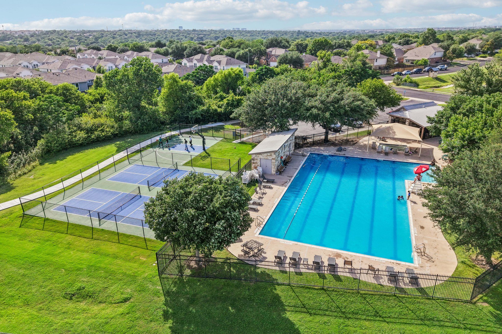 1721 Long Rifle Drive Austin, TX 78754 - Photo 36 of 38 An aerial perspective reveals a vibrant community with recreational courts and a shimmering pool set against a lush, green landscape.