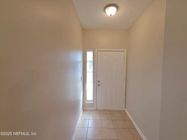 a view of a refrigerator in kitchen and an empty room in wooden floor