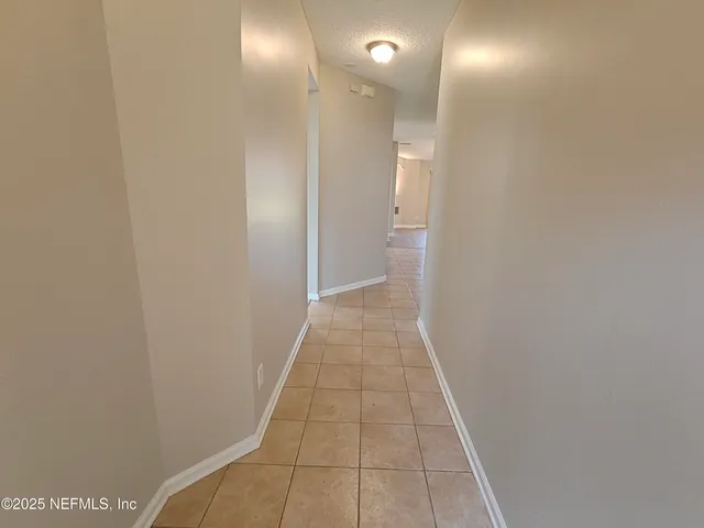 an empty room with wooden floor chandelier fan and windows
