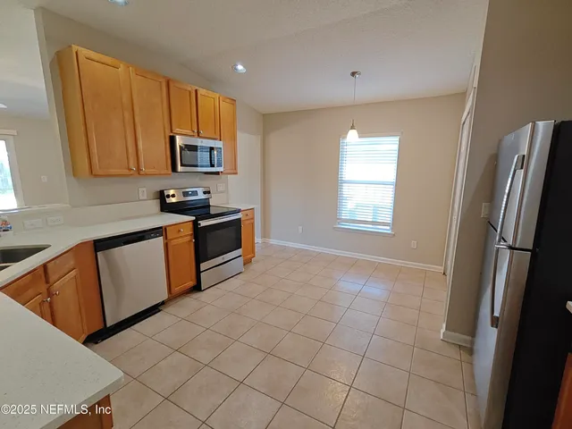 an empty room with wooden floor windows and fan