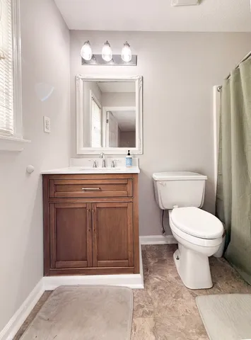 a bathroom with a toilet sink vanity and mirror
