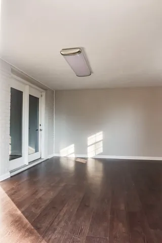 a view of an empty room with wooden floor and a window