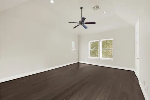 an empty room with wooden floor ceiling fan and windows