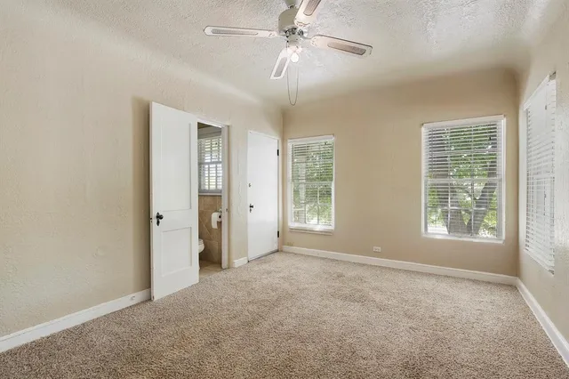 an empty room with windows and ceiling fan