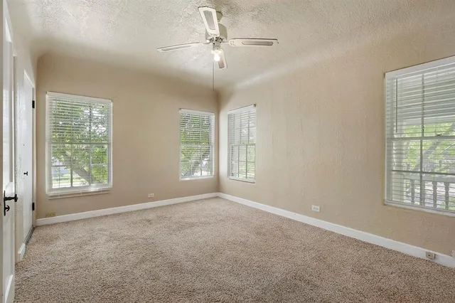 an empty room with windows and fan