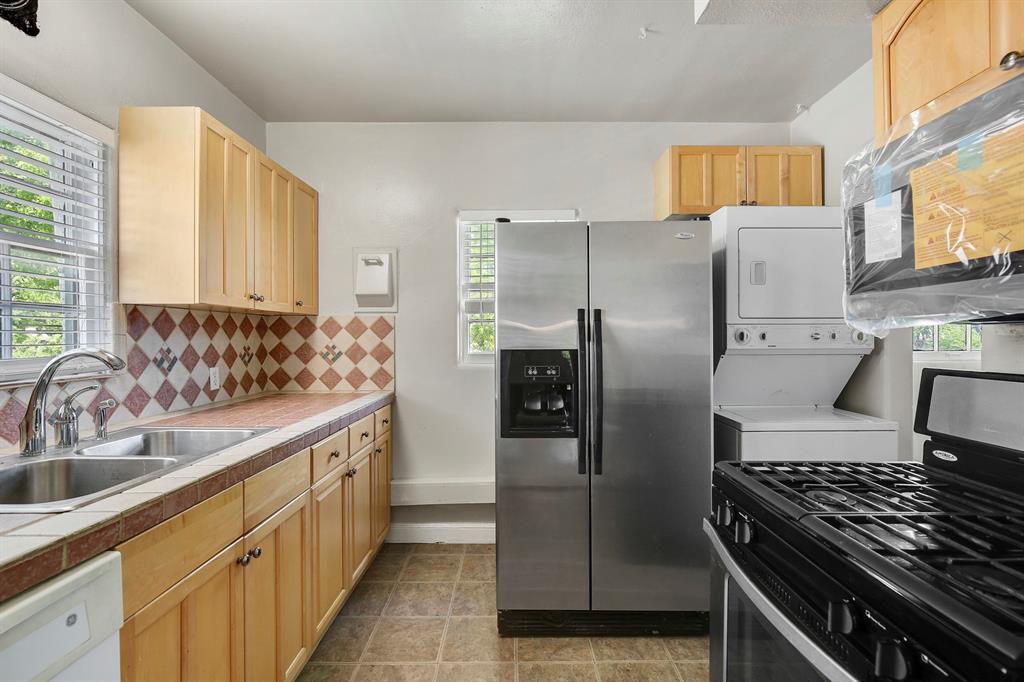 6025 Lewis Street Dallas, TX 75206 - Photo 22 of 37 a kitchen with stainless steel appliances a refrigerator sink and wooden cabinets