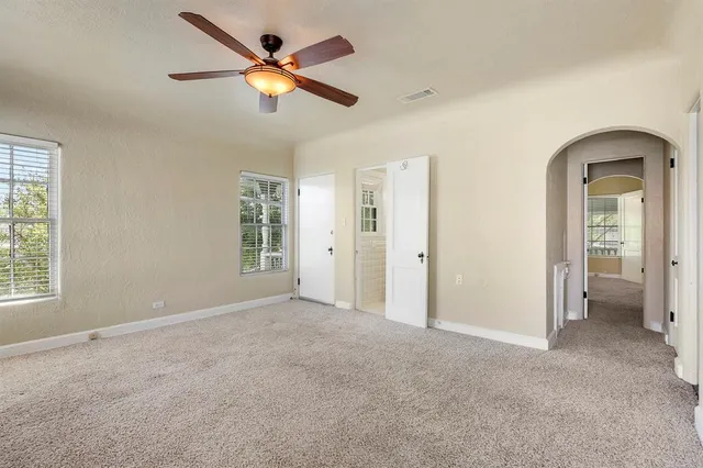 an empty room with closet and a ceiling fan