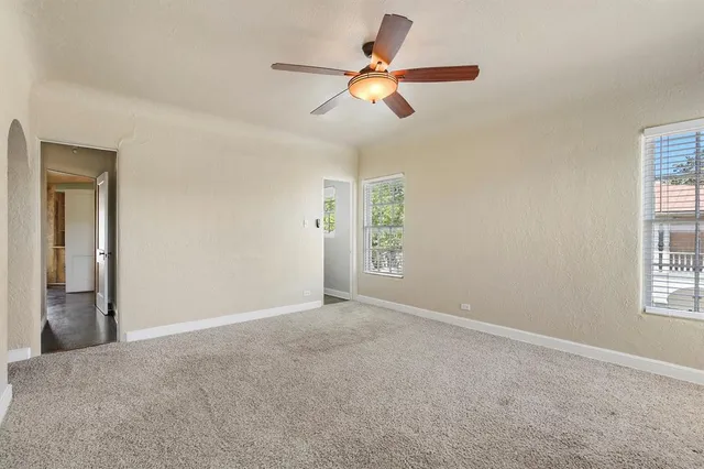 an empty room with windows and fan