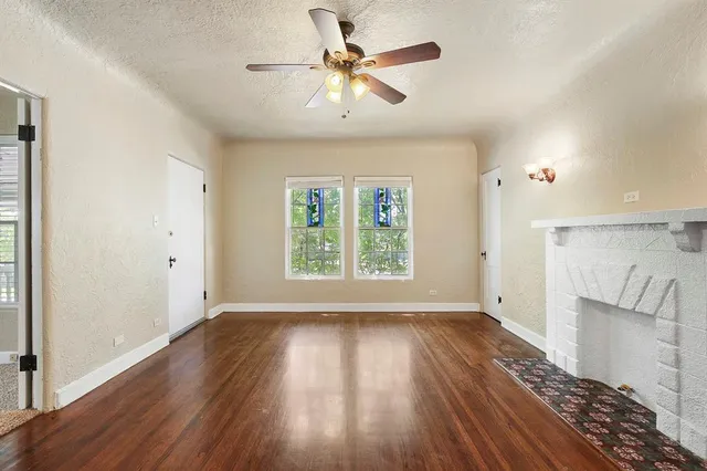 an empty room with windows and ceiling fan