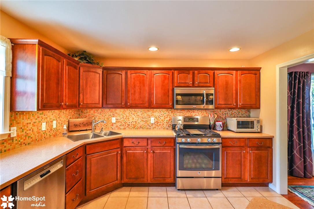 4191 Walter Road Bethlehem, PA 18020 - Photo 9 of 23 A well-equipped kitchen features rich wood cabinetry, stainless steel appliances, and a mosaic tile backsplash.
