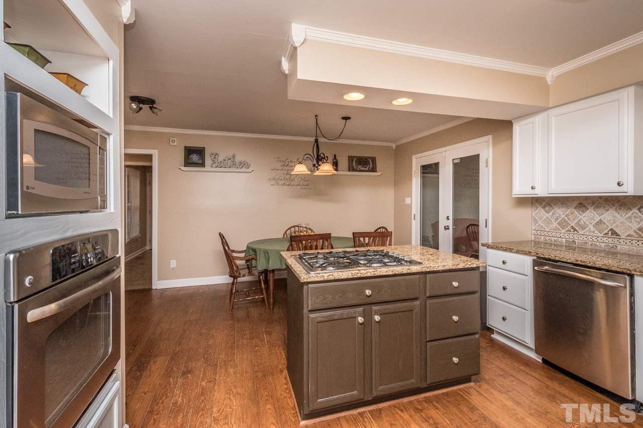 12217 Norwood Road Raleigh, NC 27613 - Photo 12 of 27 a kitchen with a stove top oven sink and cabinets