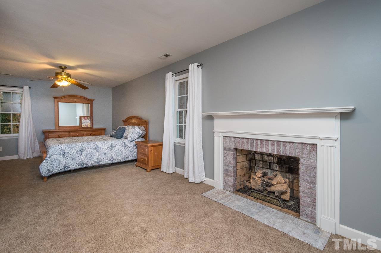 12217 Norwood Road Raleigh, NC 27613 - Photo 20 of 27 a bedroom with a bed and a fireplace