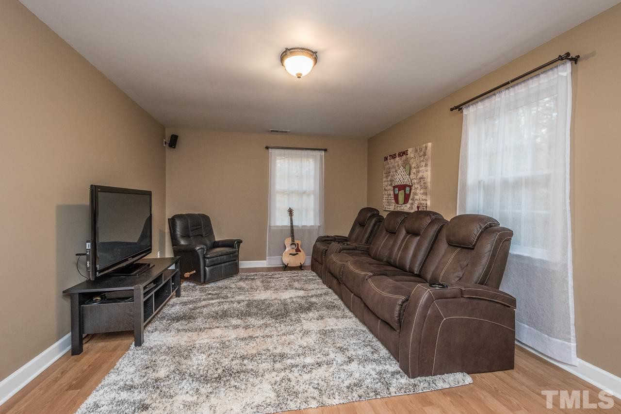12217 Norwood Road Raleigh, NC 27613 - Photo 22 of 27 a living room with furniture a flat screen tv and a window