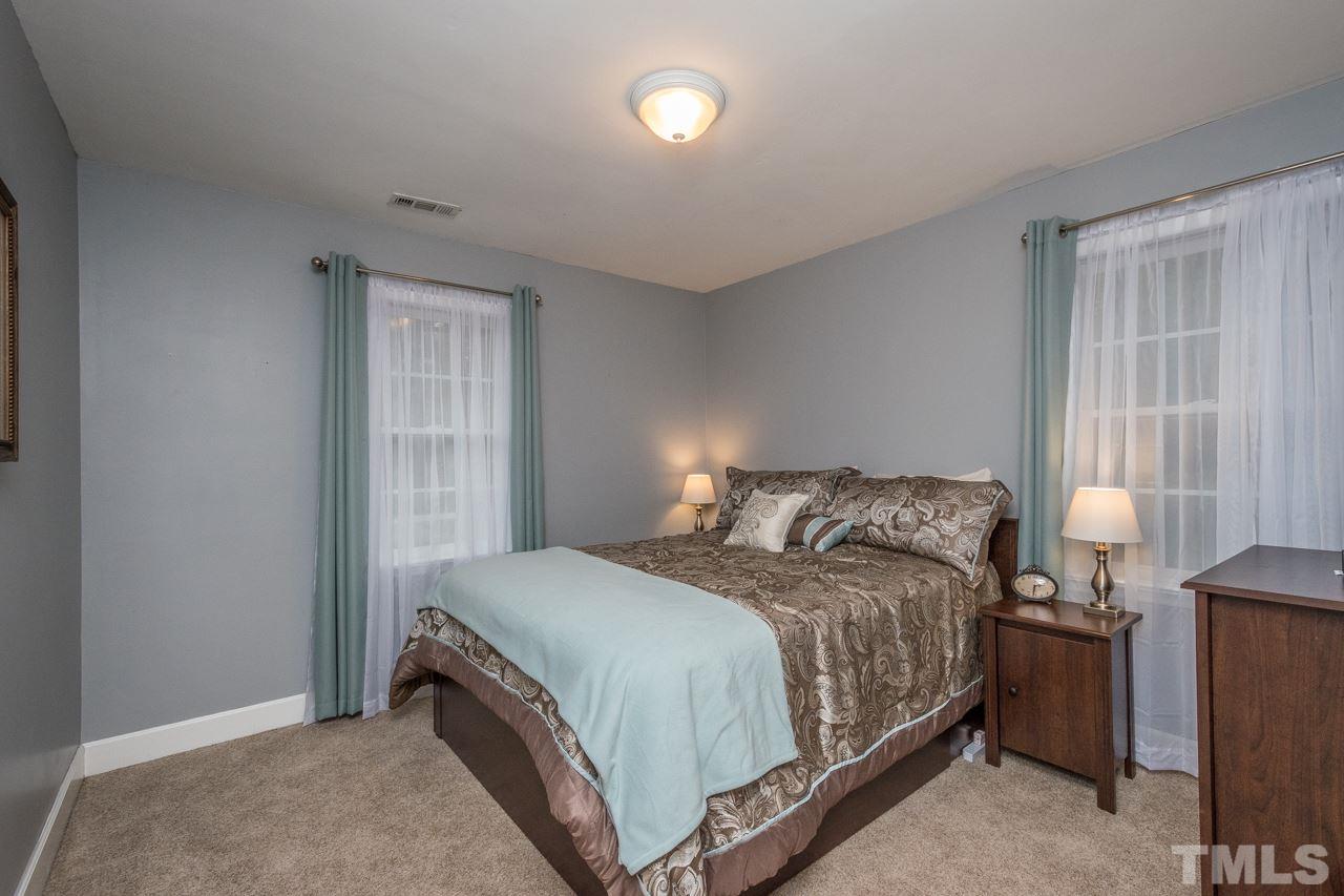 12217 Norwood Road Raleigh, NC 27613 - Photo 24 of 27 a bedroom with a bed and lamp with window