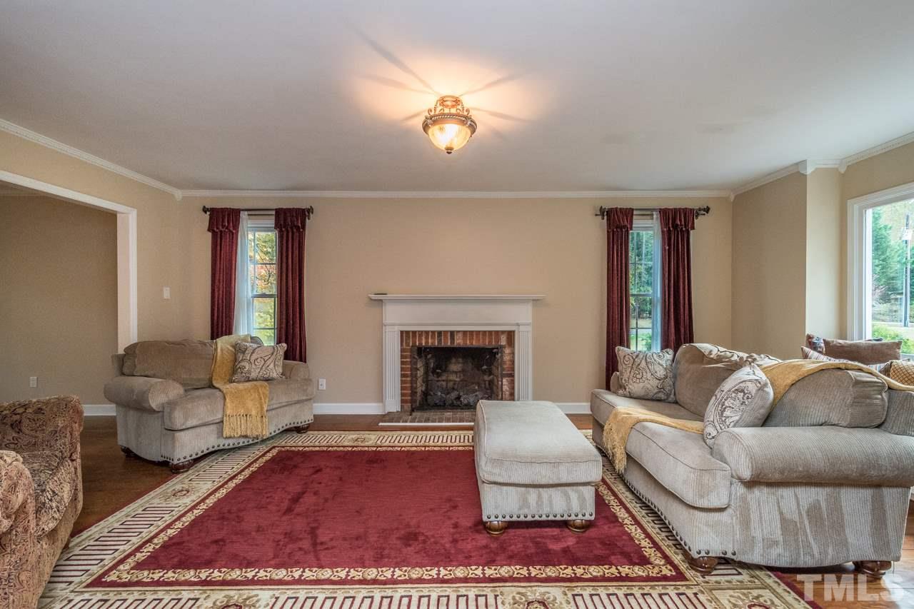 12217 Norwood Road Raleigh, NC 27613 - Photo 8 of 27 a living room with furniture a rug and a fireplace