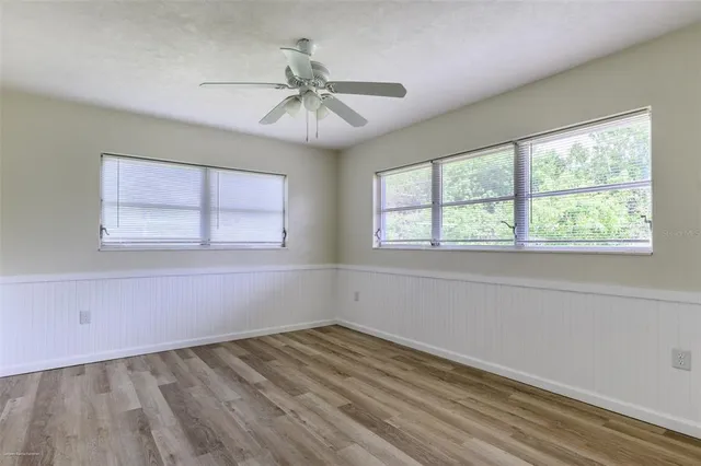 an empty room with windows and fan