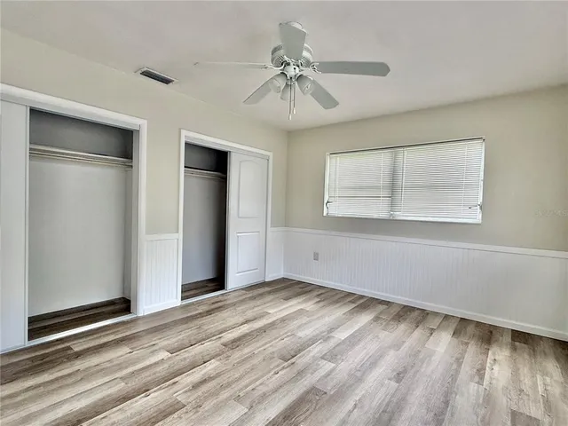 a view of empty room with wooden floor and fan