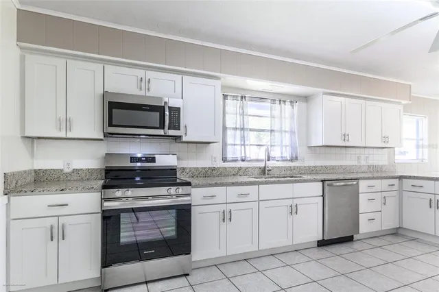 a kitchen with cabinets appliances a sink and a window