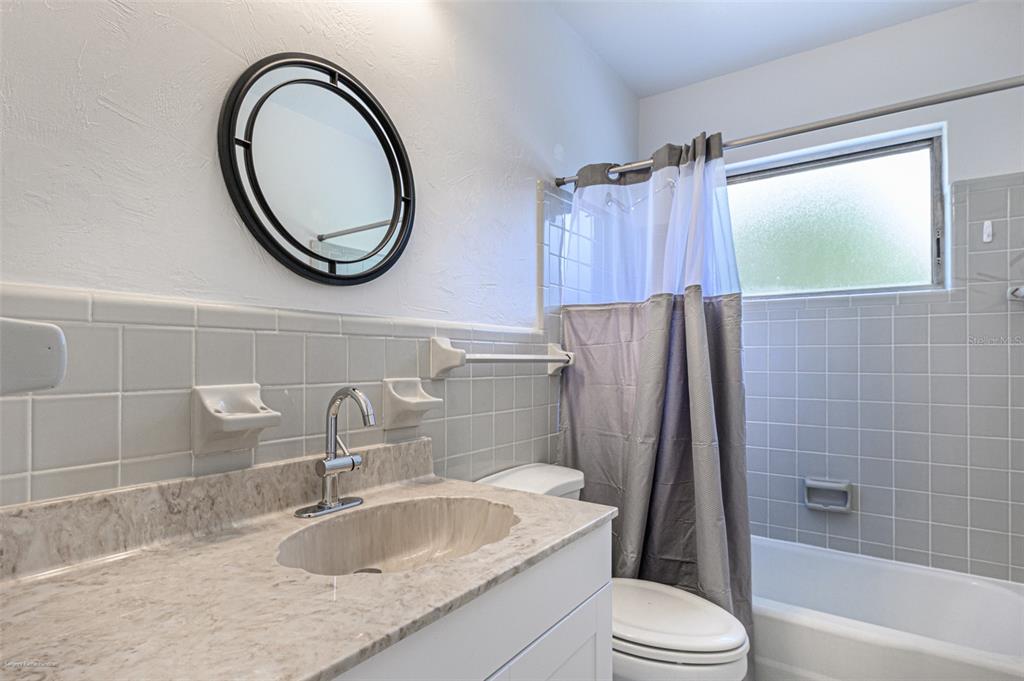 1214 Ansin Street Punta Gorda, FL 33950 - Photo 21 of 24 a bathroom with a granite countertop sink a toilet and a mirror
