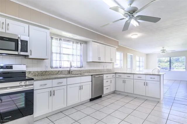 a kitchen with granite countertop white cabinets white appliances with a sink and dishwasher