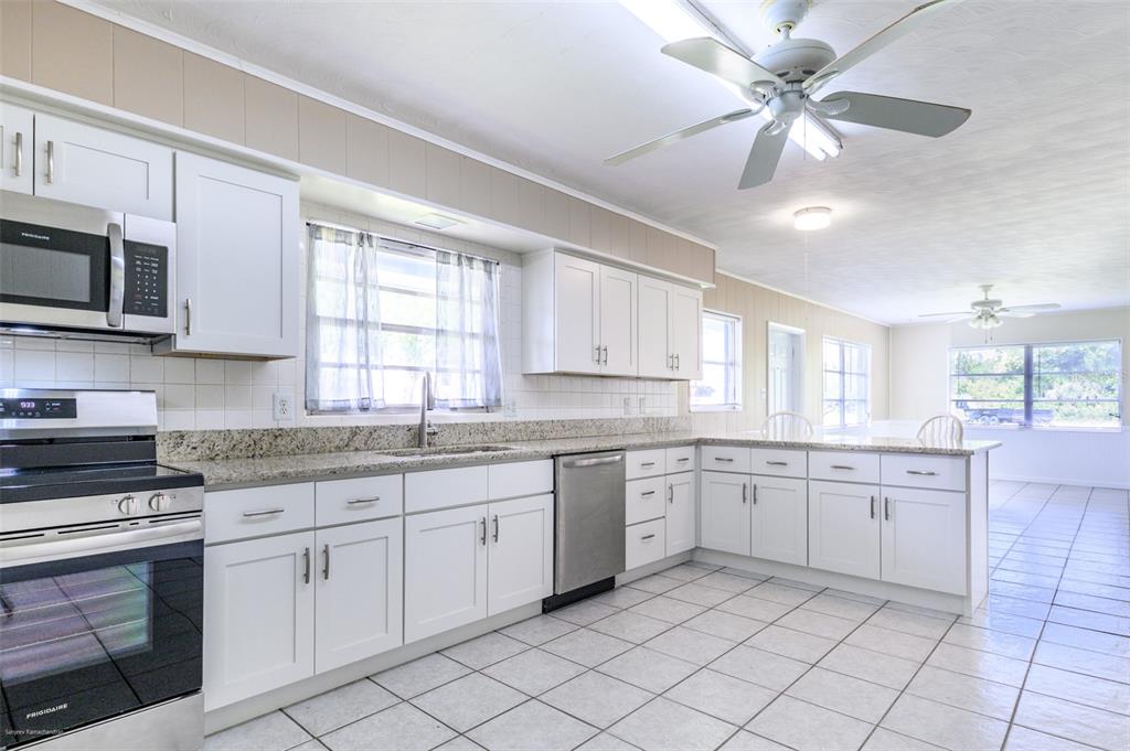 1214 Ansin Street Punta Gorda, FL 33950 - Photo 3 of 24 a kitchen with granite countertop white cabinets white appliances with a sink and dishwasher