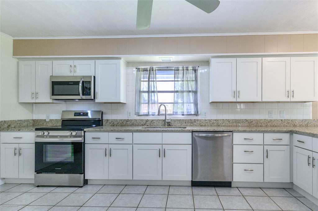 1214 Ansin Street Punta Gorda, FL 33950 - Photo 6 of 24 a kitchen with white cabinets appliances a sink and a window