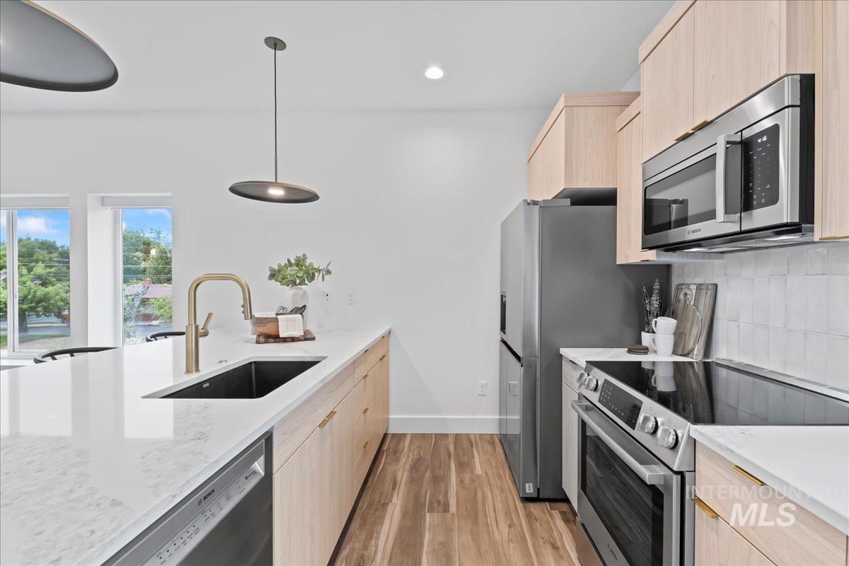 1011 South Orchard Street, Unit 101 Boise, ID 83705 - Photo 1 of 16 Kitchen with light cabinets, stainless steel appliances, dark floors, quartz counters, and recessed lighting.