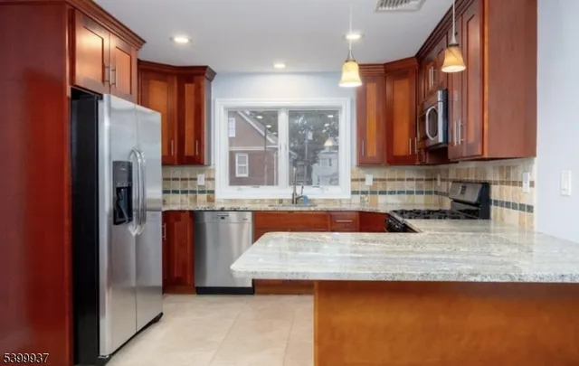 a kitchen with stainless steel appliances granite countertop a refrigerator a stove and a sink