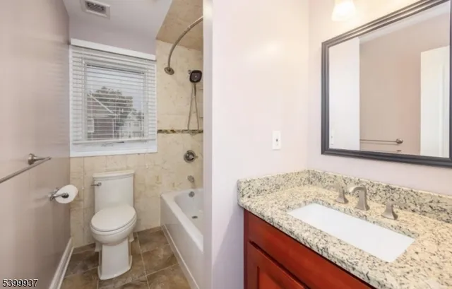 a bathroom with a granite countertop sink toilet a large mirror a shower and a bathtub