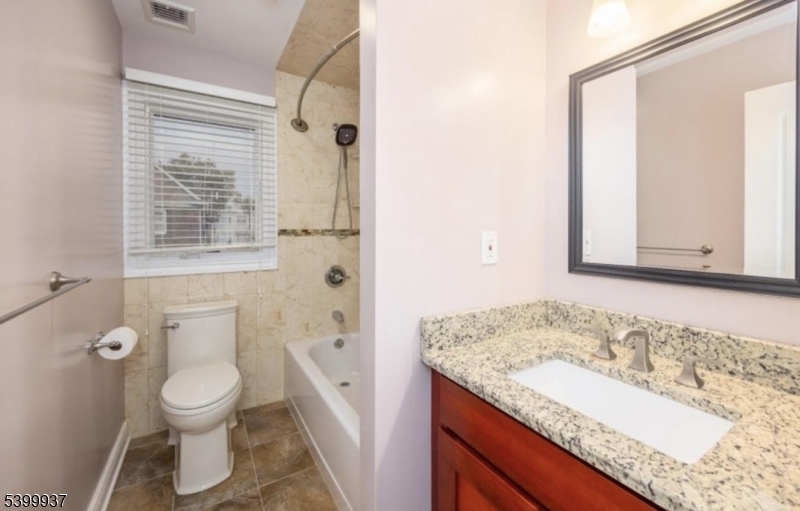 71 Christie Avenue, Unit 2 Clifton, NJ 07011 - Photo 4 of 8 a bathroom with a granite countertop sink toilet a large mirror a shower and a bathtub
