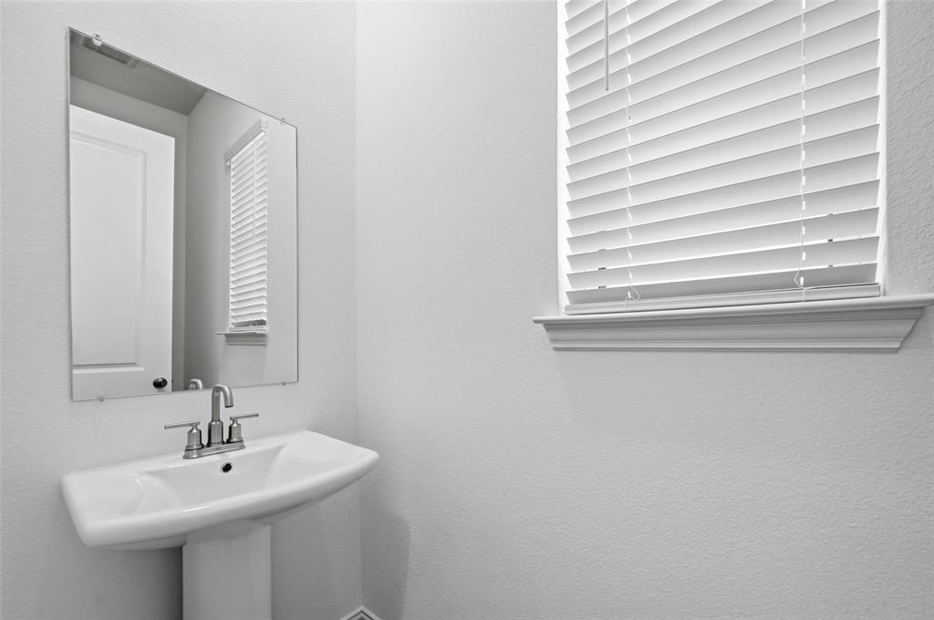 1168 Daybreak Drive, Unit 1168 Allen, TX 75013 - Photo 7 of 25 Pedestal sink with a polished chrome faucet, rectangular mirror, and a window featuring white horizontal blinds