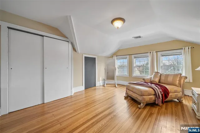 a spacious bedroom with a bed and wooden floor