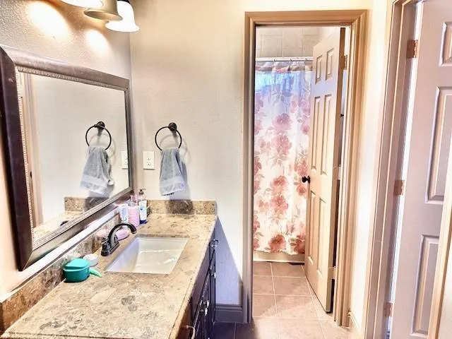 a bathroom with a granite countertop sink a mirror and shower
