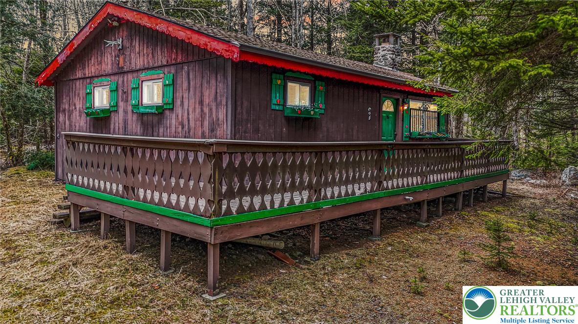 a view of a wooden house with a small deck and wooden fence