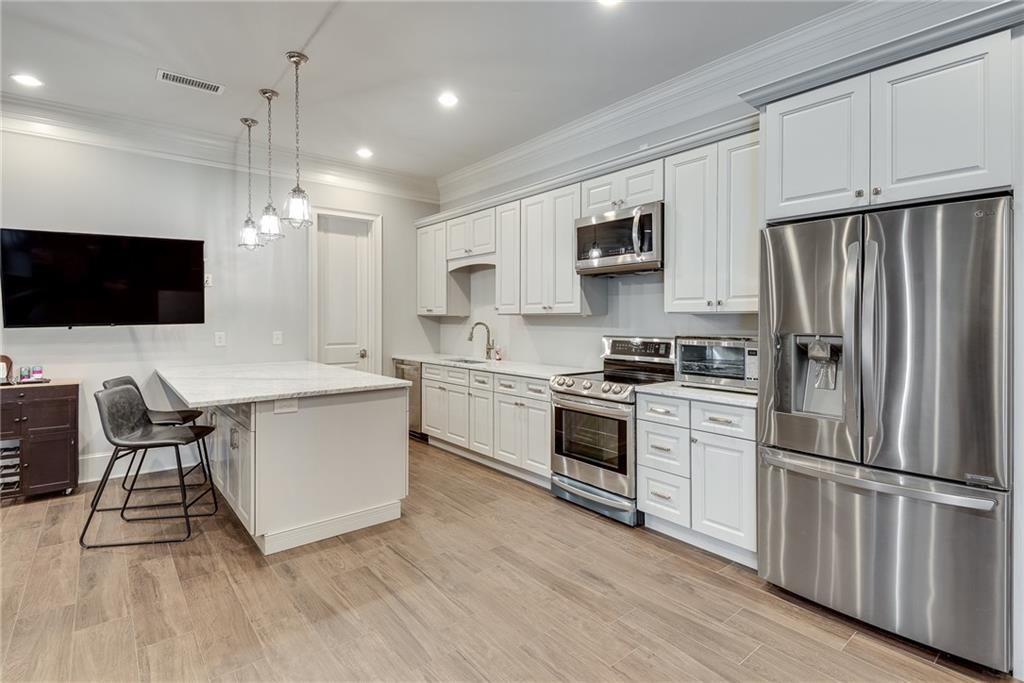 187 Fontaine Road Southwest Mableton, GA 30126 - Photo 58 of 84 a kitchen with stainless steel appliances a stove a sink dishwasher a refrigerator white cabinets and wooden floor