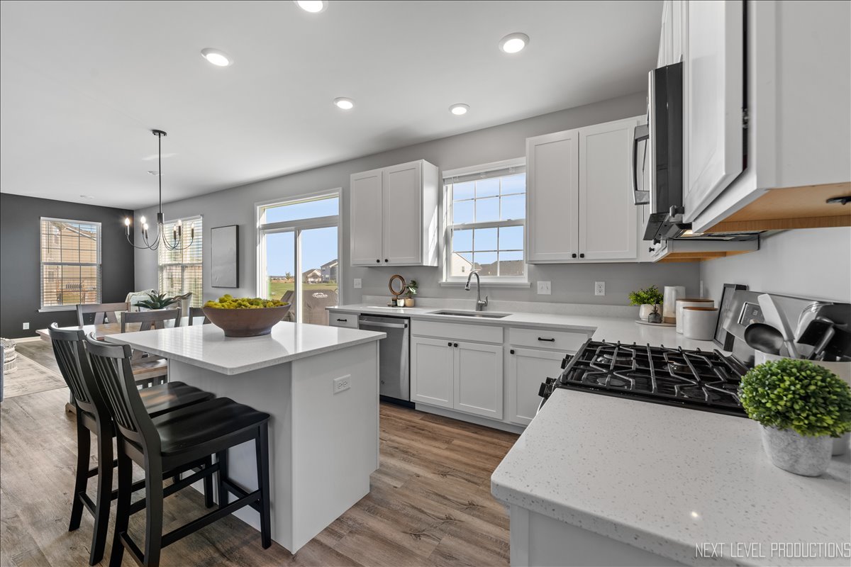 2236 Fairfax Way Yorkville, IL 60560 - Photo 7 of 28 a kitchen with a sink a stove a refrigerator and white cabinets with wooden floor