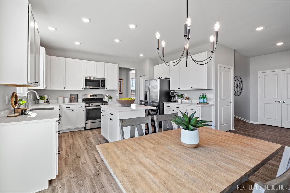 2236 Fairfax Way Yorkville, IL 60560 - Photo 9 of 28 a kitchen with white cabinets stainless steel appliances and dining table