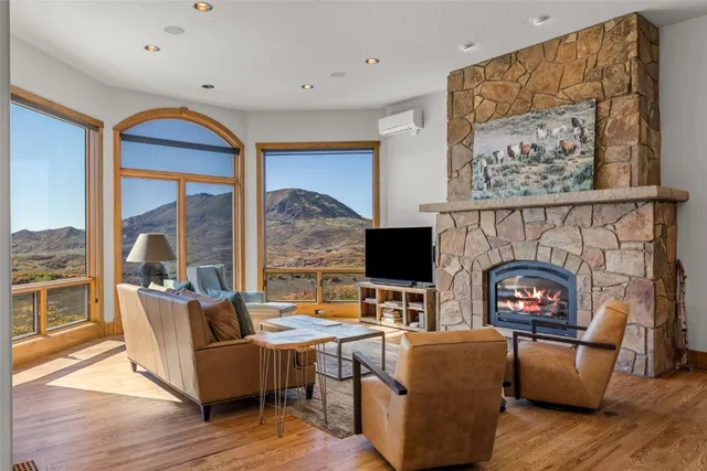 a living room with furniture a fireplace and a floor to ceiling window